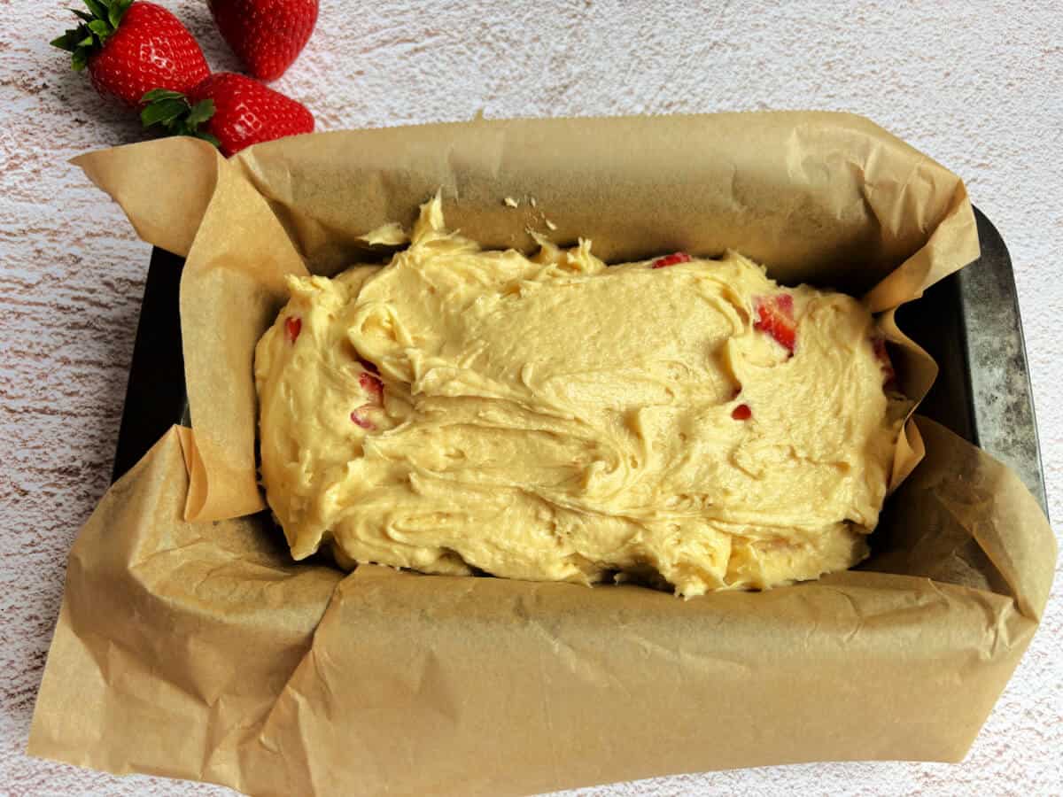 Lined loaf cake tin with cake batter in it.