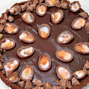 Close up of a chocolate tart with halved creme eggs on top.