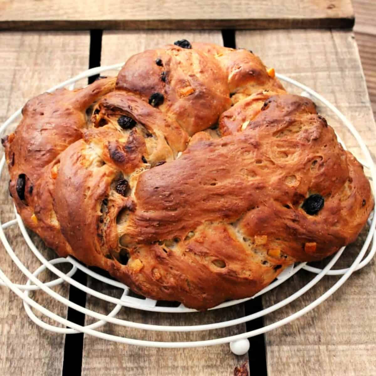 Fruit bread formed into a bread crown shape, on white cooling rack.