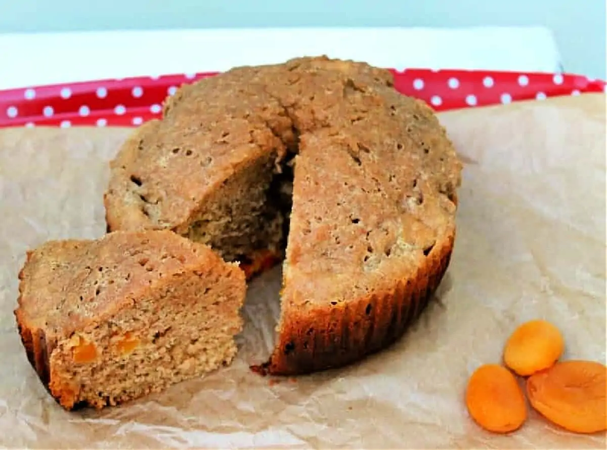 Cake with a slice cut out of it, dried apricots to the side.