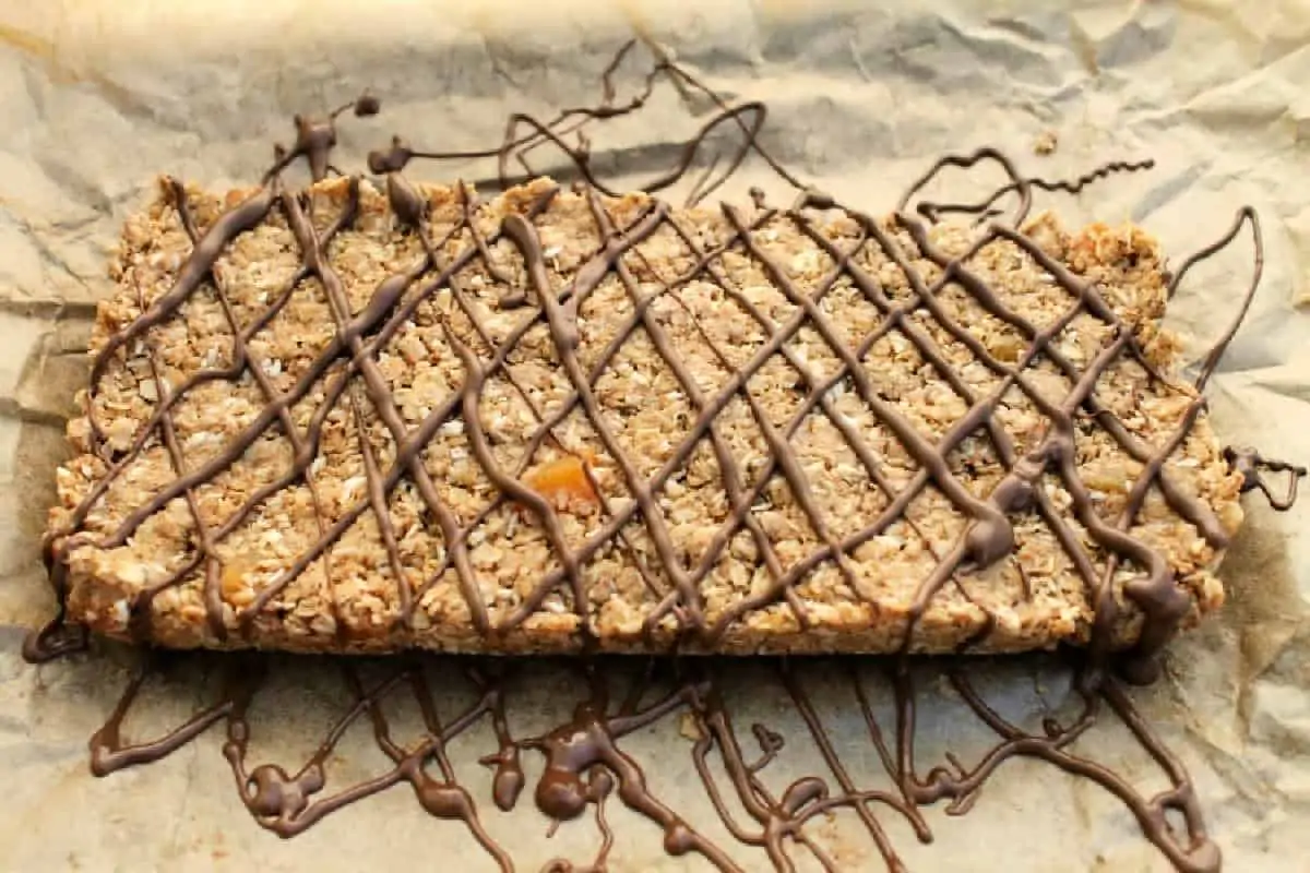 No bake oat bars drizzled with chocolate in a diamond pattern, on baking parchment.