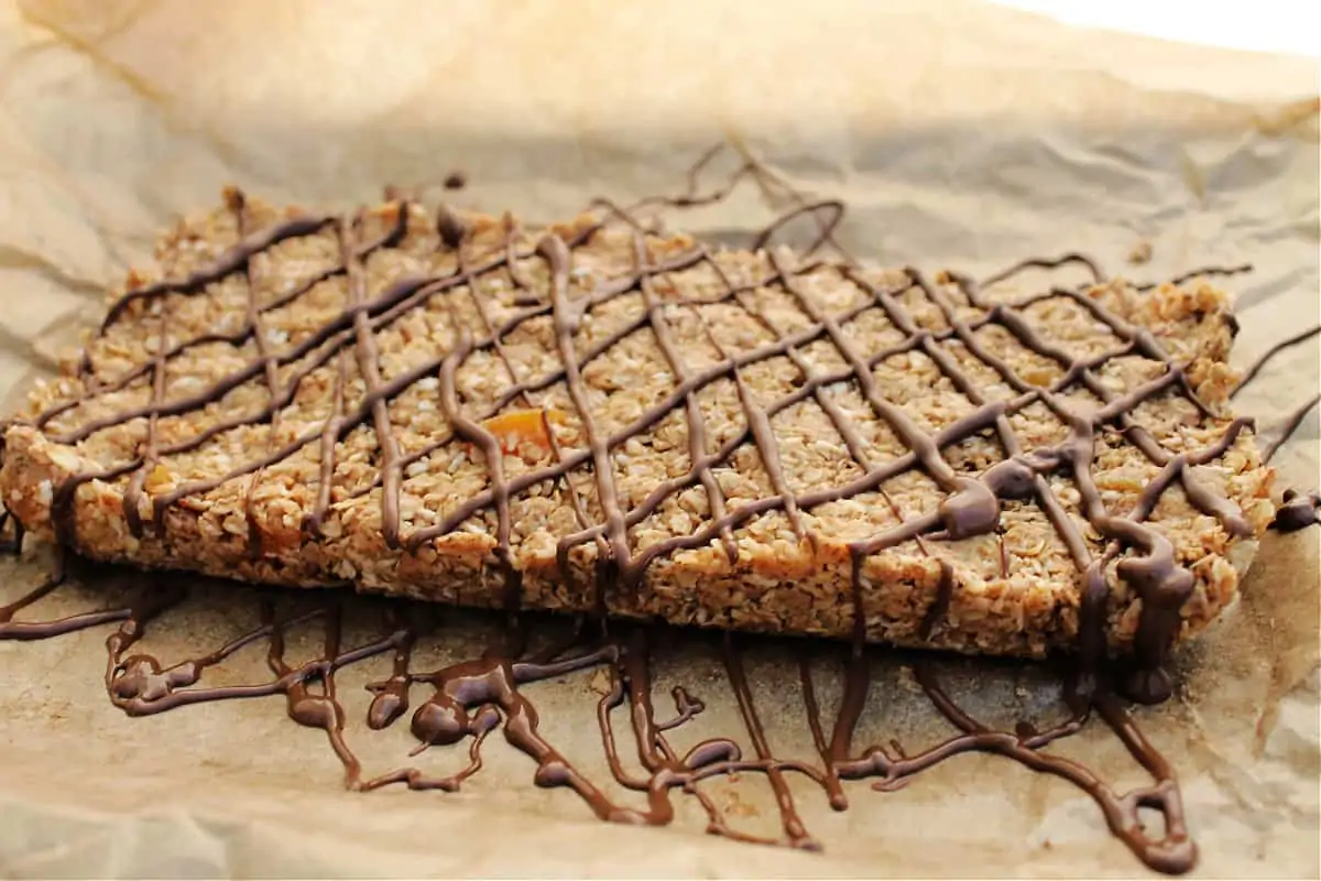 No bake oat bars drizzled with chocolate in a diamond pattern, on baking parchment.