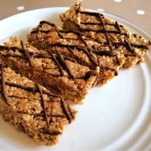 Oat bars with chocolate drizzle on a white plate.