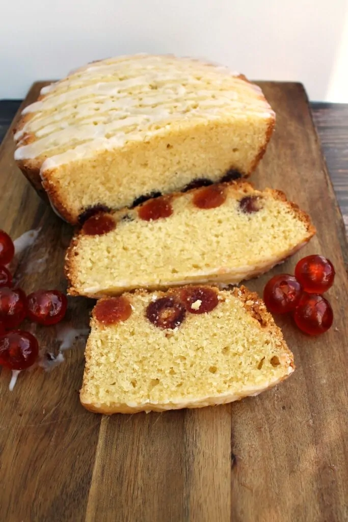 Cherry cake sliced into slices on a board, with cherries around.