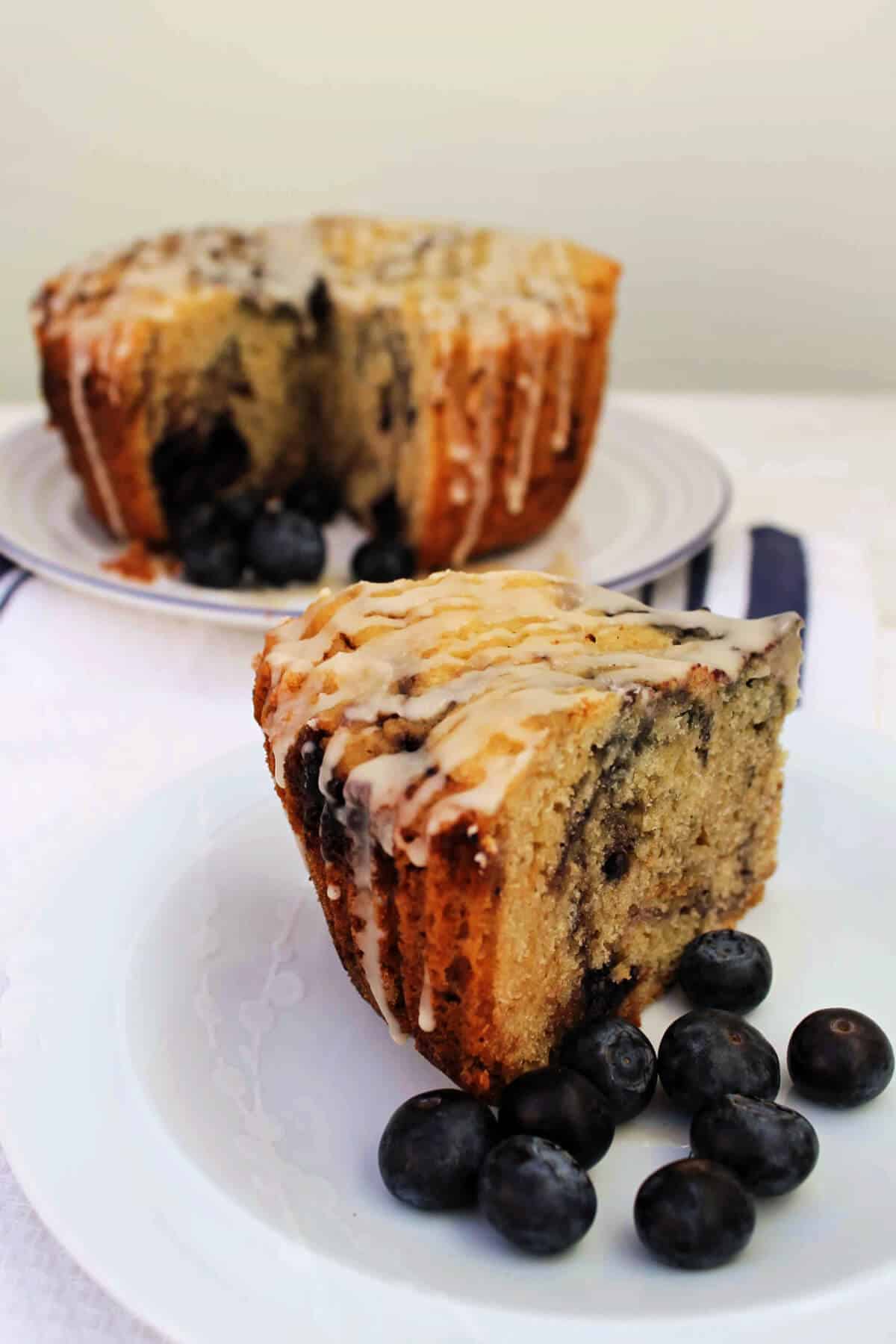 Slice of cake with marbled jam and blueberries on a white plate.