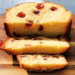 Close up of round cherry cake, slices cut showing the cherries inside.