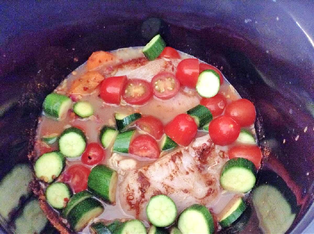 Chicken and vegetables in slow cooker pot.