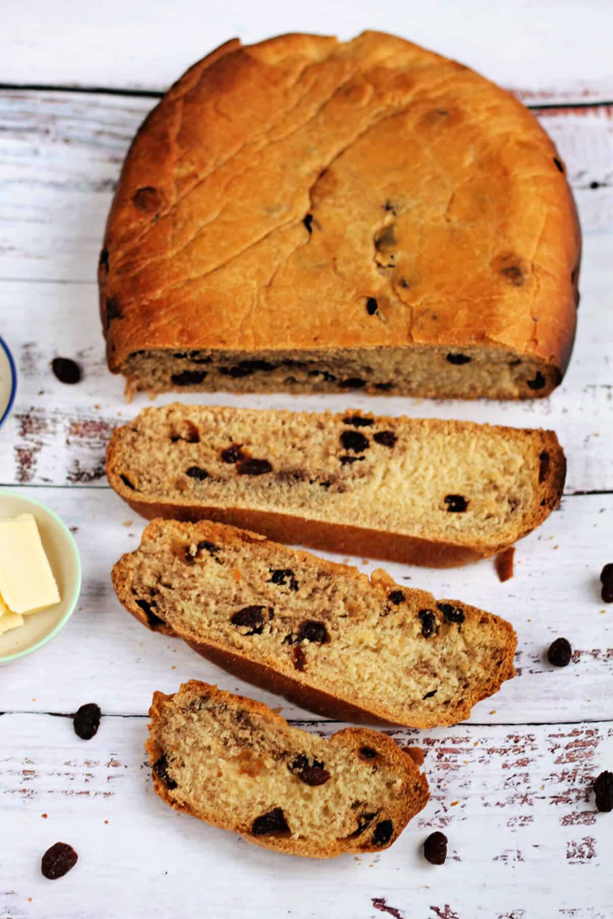 Loaf of cinnamon raisin bread on white table, sliced.