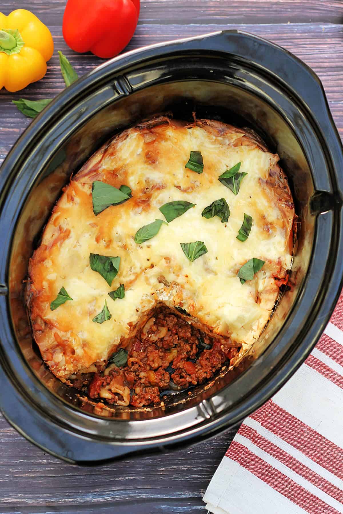 Slow cooker pot containing cooked lasagne garnished with basil.