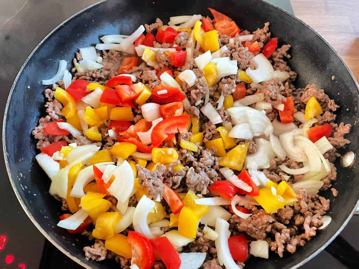 Pan with onion and peppers added to minced beef. 