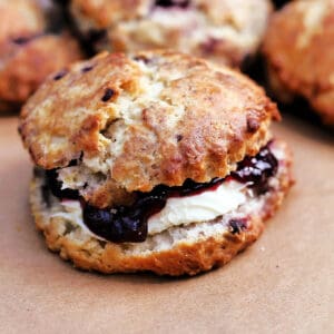Close up of blackberry scone filled with jam and cream.