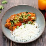 Sweet and sour pork with rice in grey bowl.