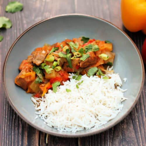 Sweet and sour pork with rice in grey bowl.