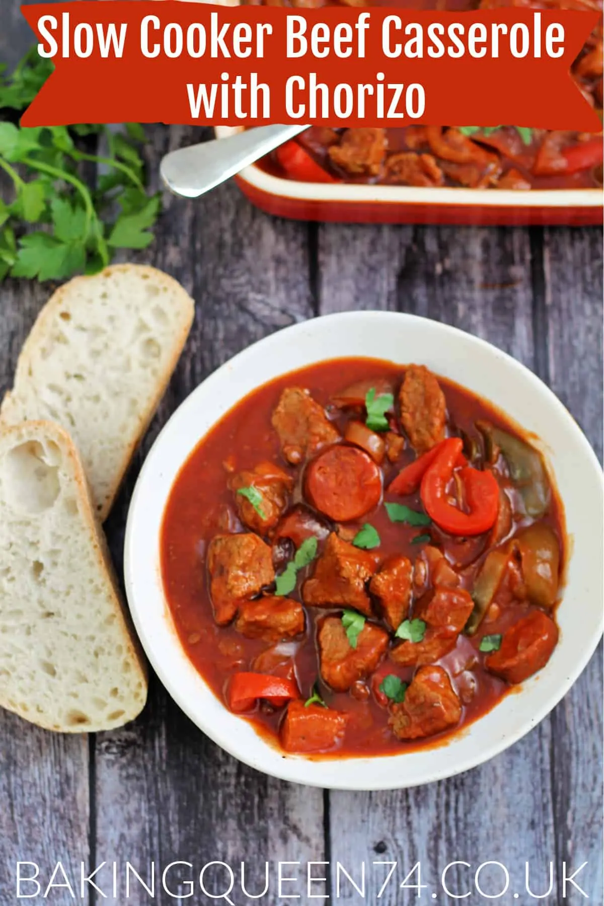 Bowl of beef casserole served with crusty bread on the side, with herbs and serving dish behind, with text overlay (slow cooker beef casserole with chorizo).