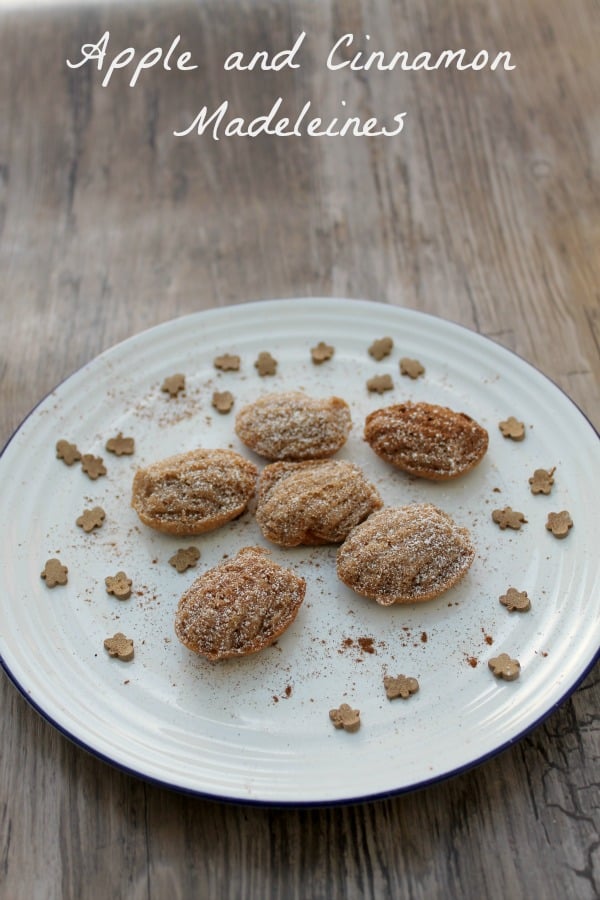 Mini madeleines on a white plate on a wooden table with text overlay.