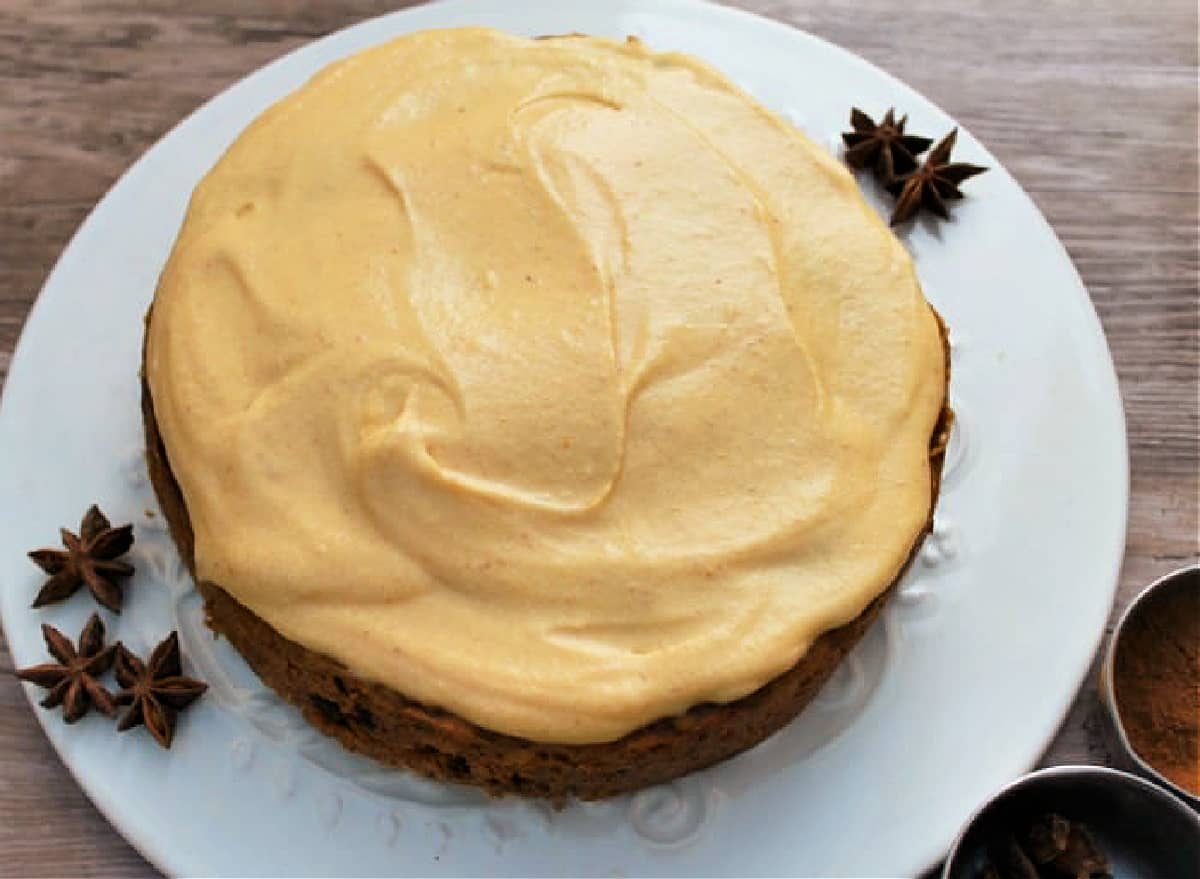 Overhead view of cake with pumpkin frosting on a white plate, with star anise.