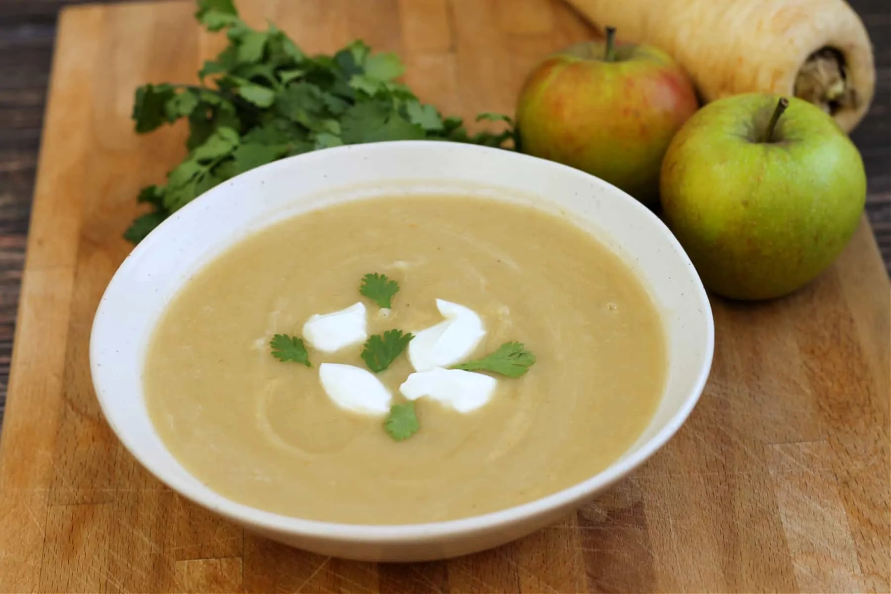 Bowl of soup topped with swirls of creme fraiche and coriander leaves.