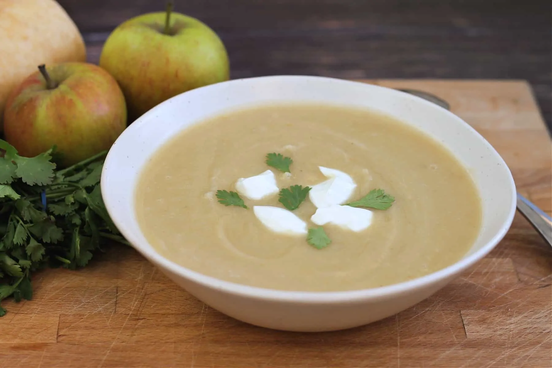 Bowl of soup topped with swirls of creme fraiche and coriander leaves.