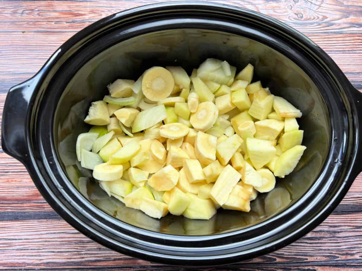 Chopped veg in slow cooker pot.