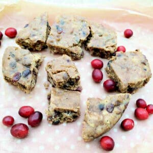 Squares of fruit cake with fresh cranberries, on a tray.