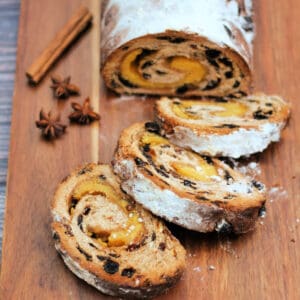 Stollen loaf on wooden board, with slices cut off.