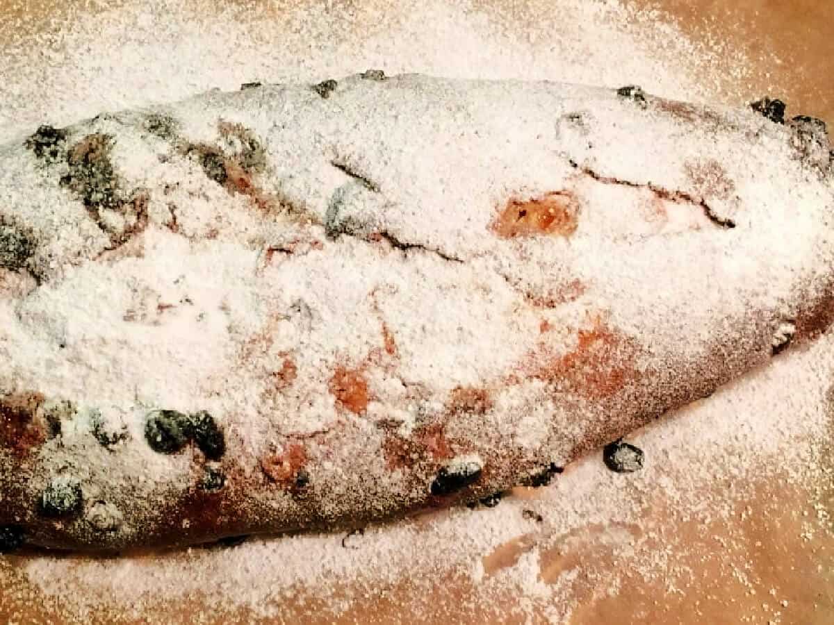 Baked stollen on baking tray, dusted with icing sugar.