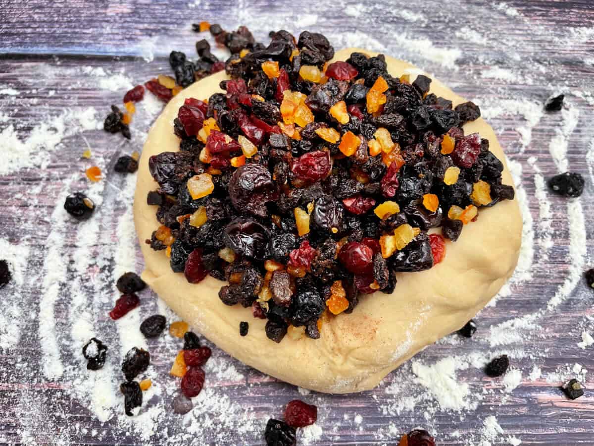 Ball of dough with dried fruit on it, ready to incorporate.