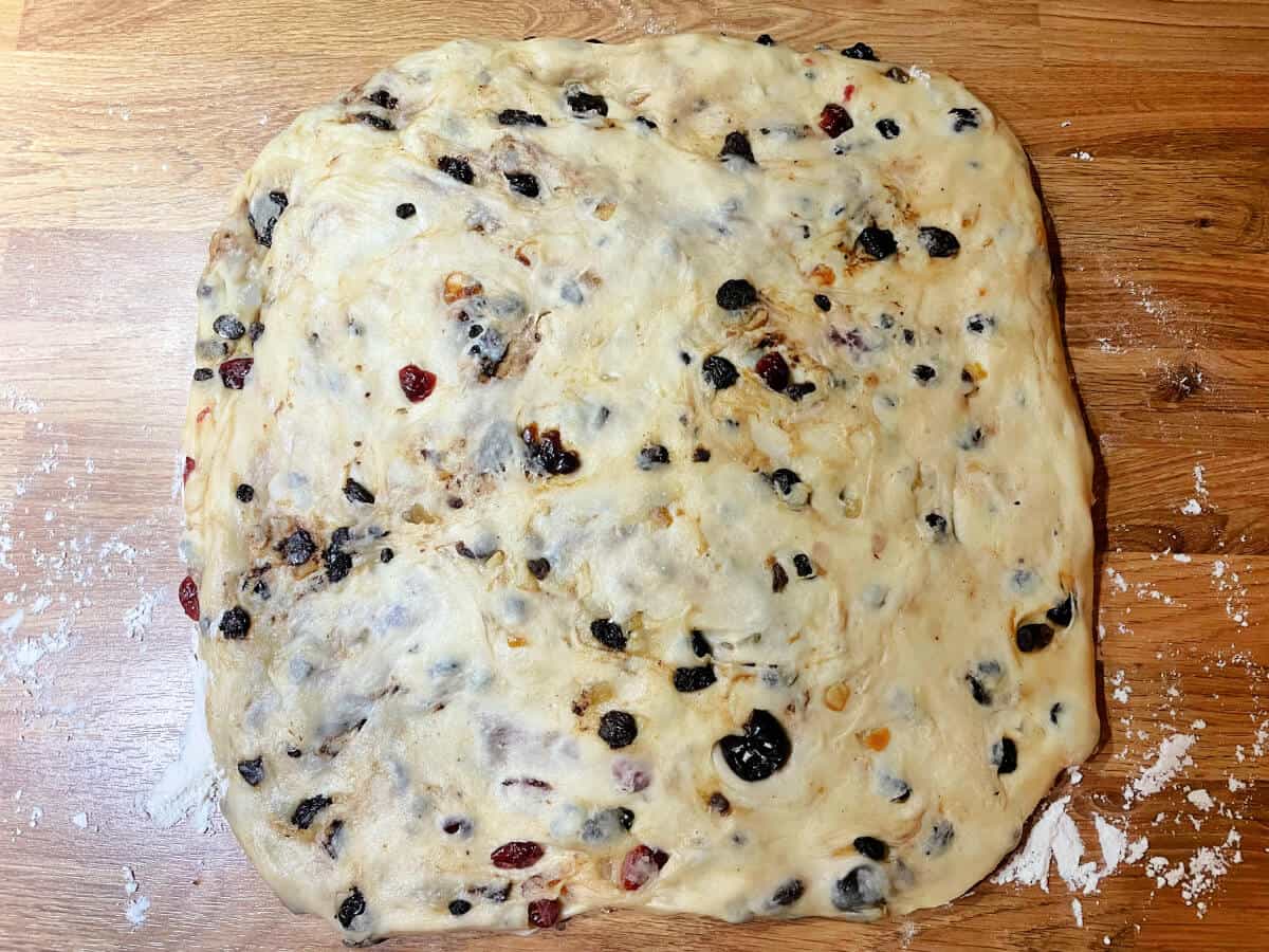 Stollen dough rolled out into a large rectangle on wooden surface.