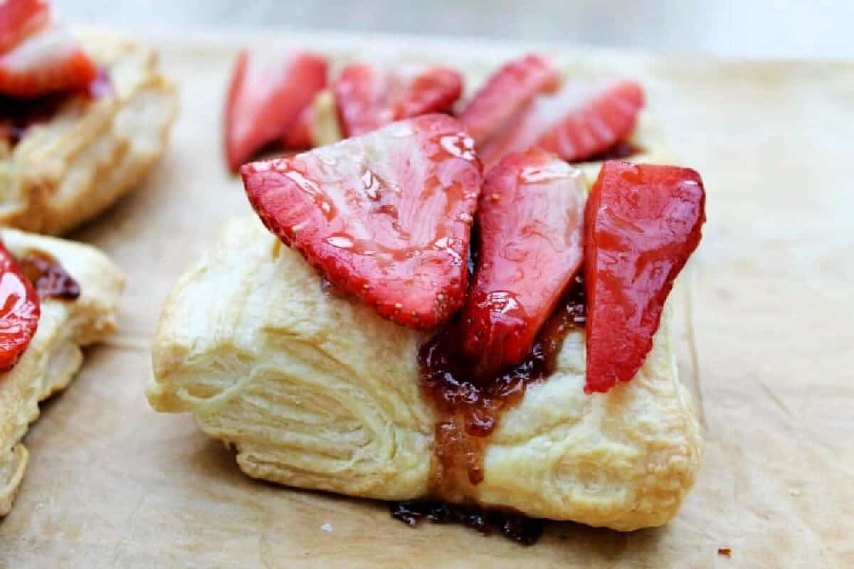 Halved strawberries on top of a puff pastry square, glazed with jam.