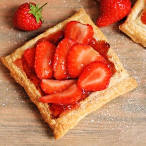 A square strawberry tart with puff pastry shell, strawberry jam and sliced fresh strawberries.