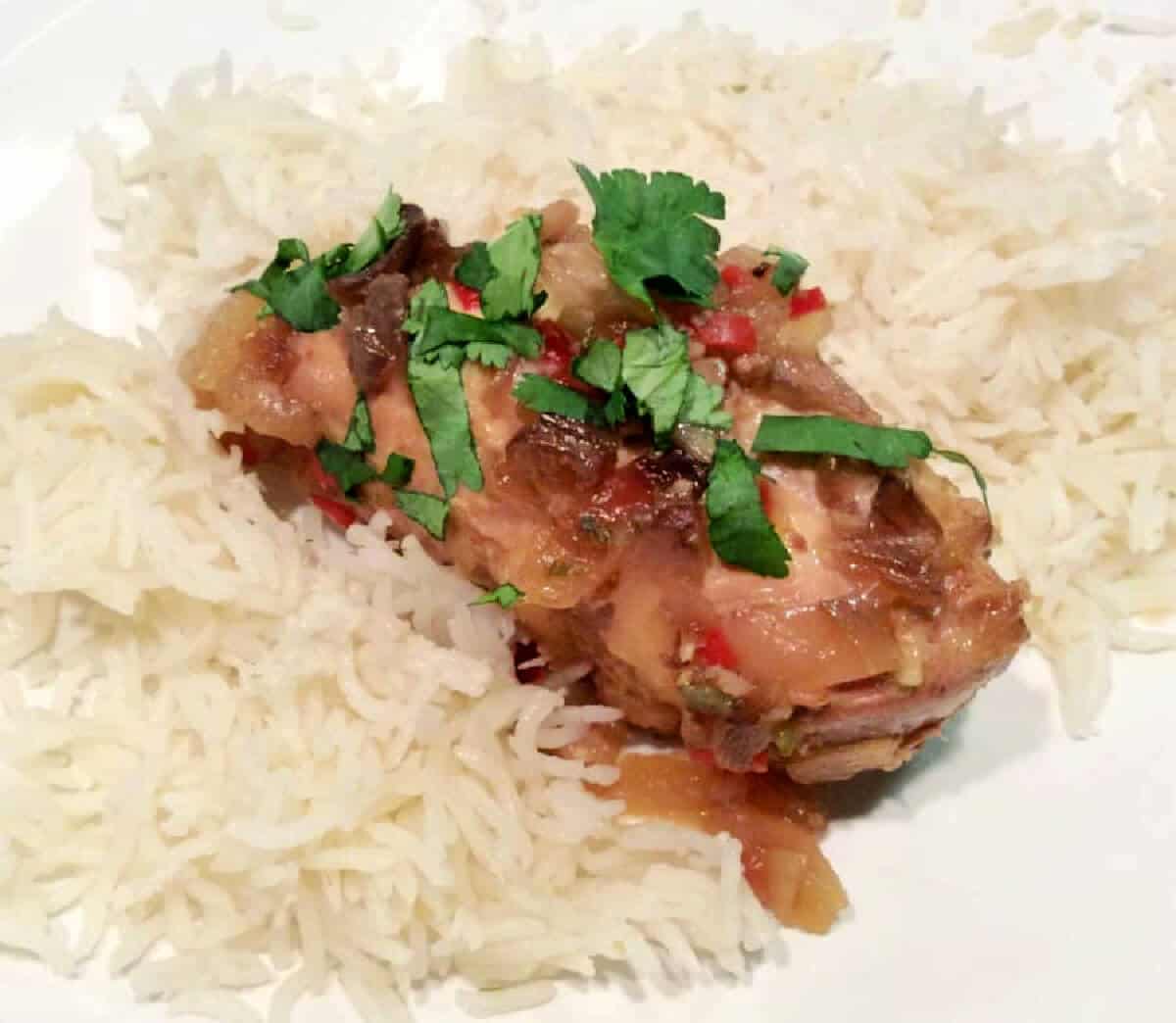 Chilli lime chicken with rice on white plate, with coriander garnish.