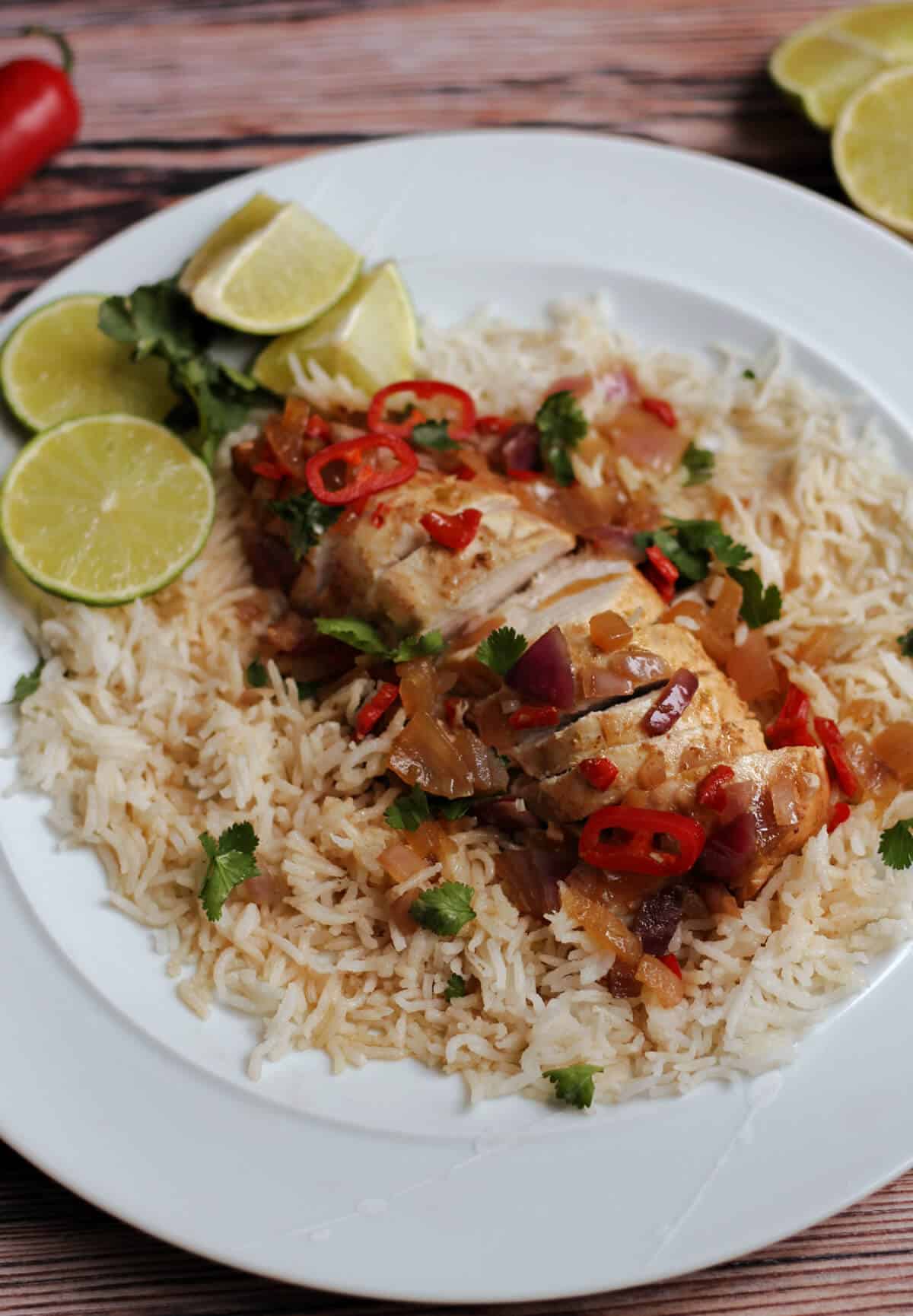 Sliced chicken breast on rice with lemon wedges.