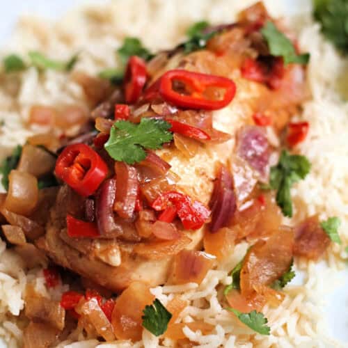 Chicken breast garnished with red chilli slices and fresh coriander leaves, on rice.