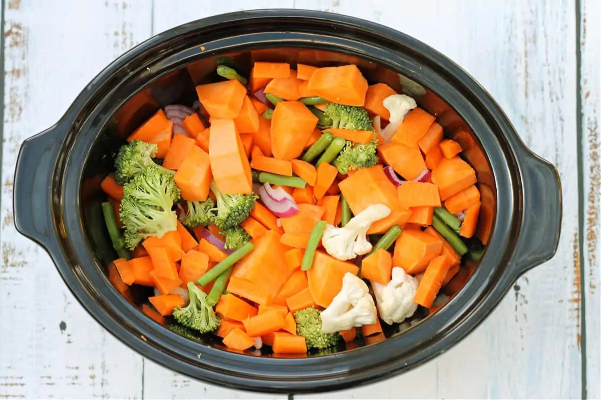 Slow cooker pot filled with prepared vegetables.