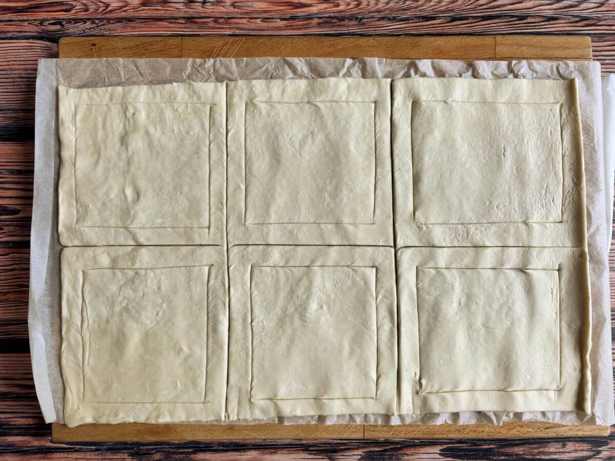Puff pastry sheet cut into equal parts with an edge scored onto each.