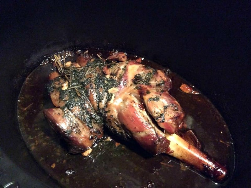 Cooked leg of lamb in slow cooker pot.