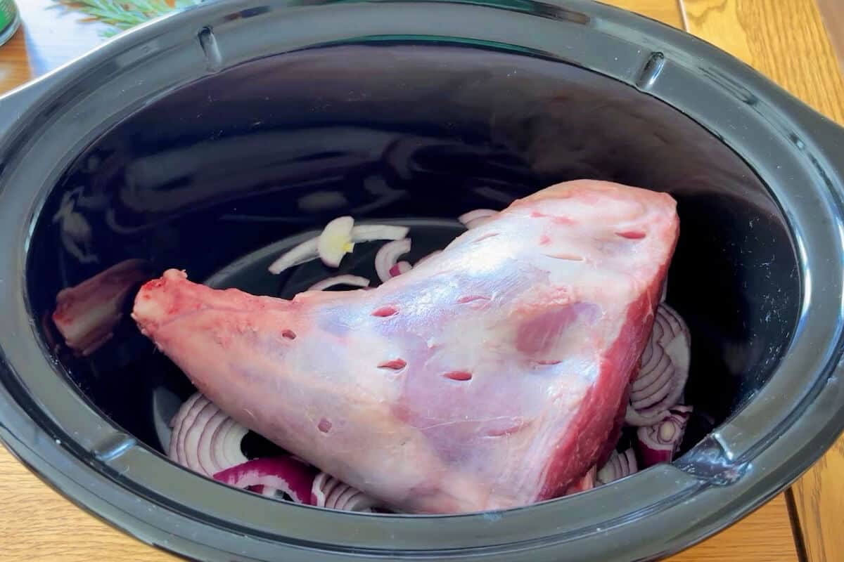 Lamb leg with incisions in slow cooker.