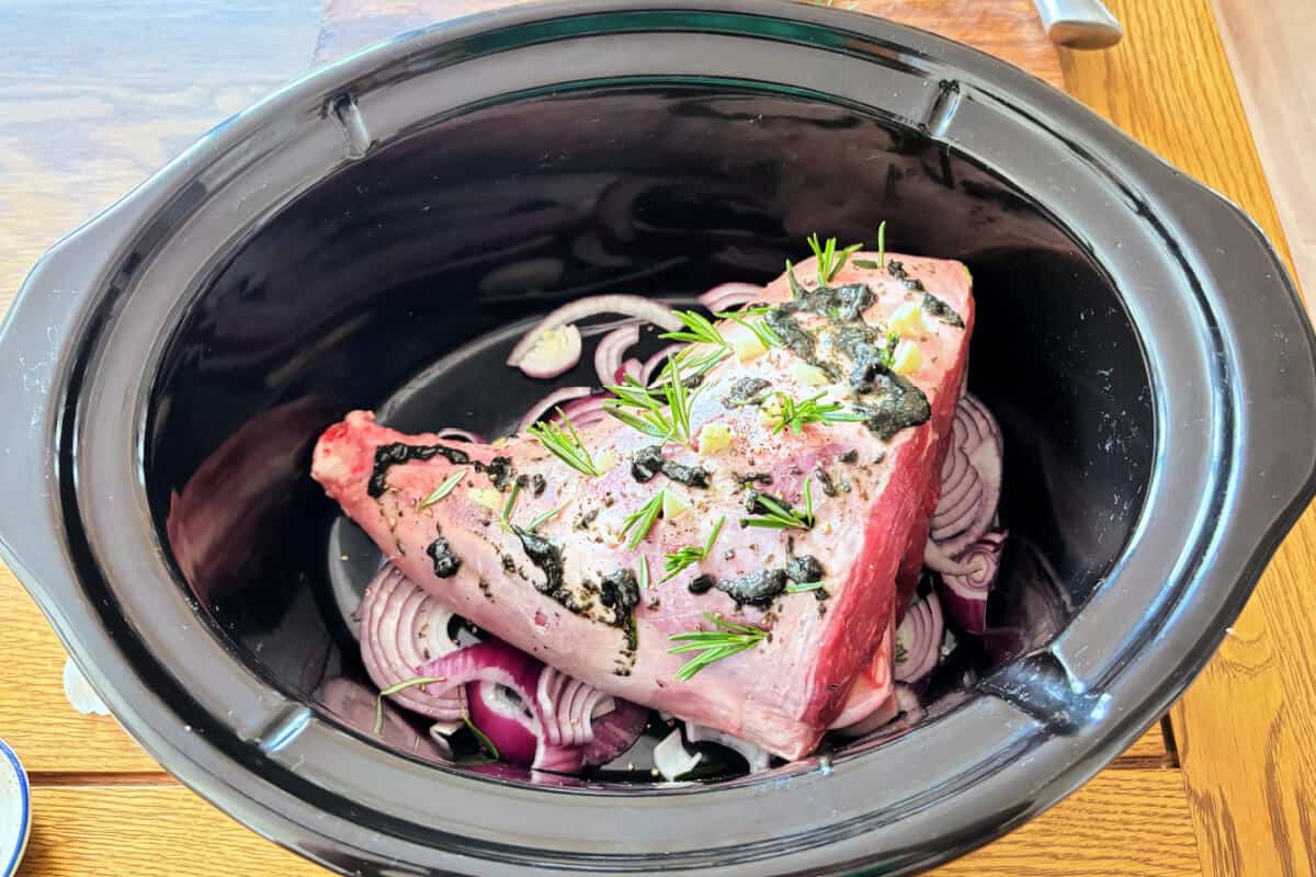 Lamb with garlic, rosemary and mint sauce, in slow cooker pot.