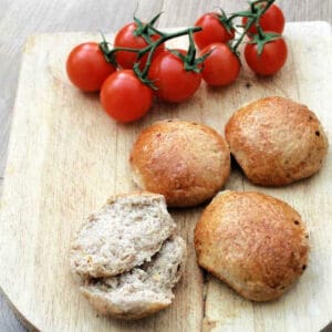 Rolls on a wooden board, with tomatoes on the vine.