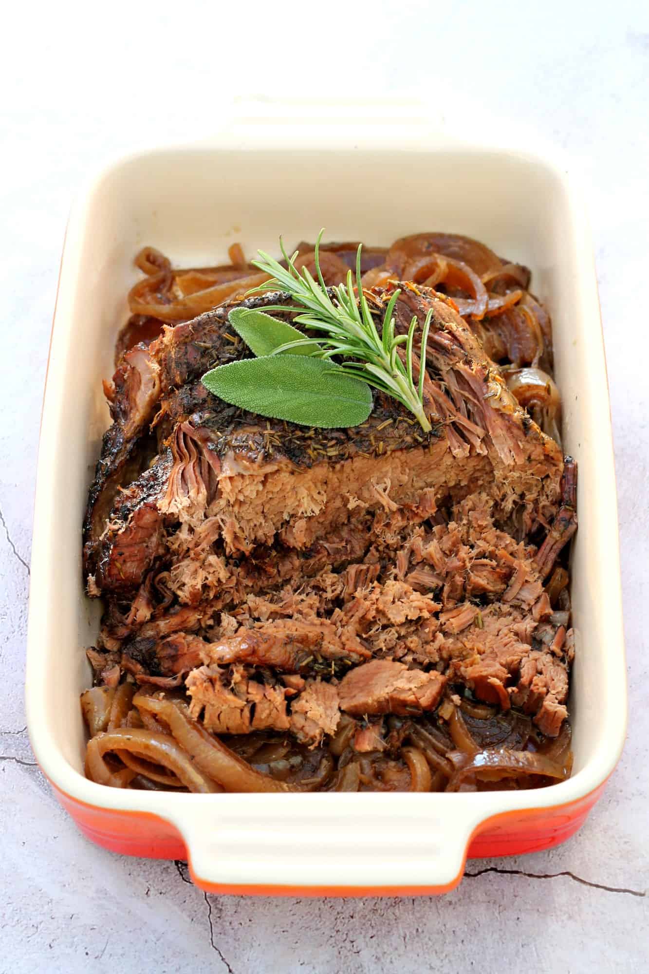 Brisket beef in serving dish, sliced and falling apart.