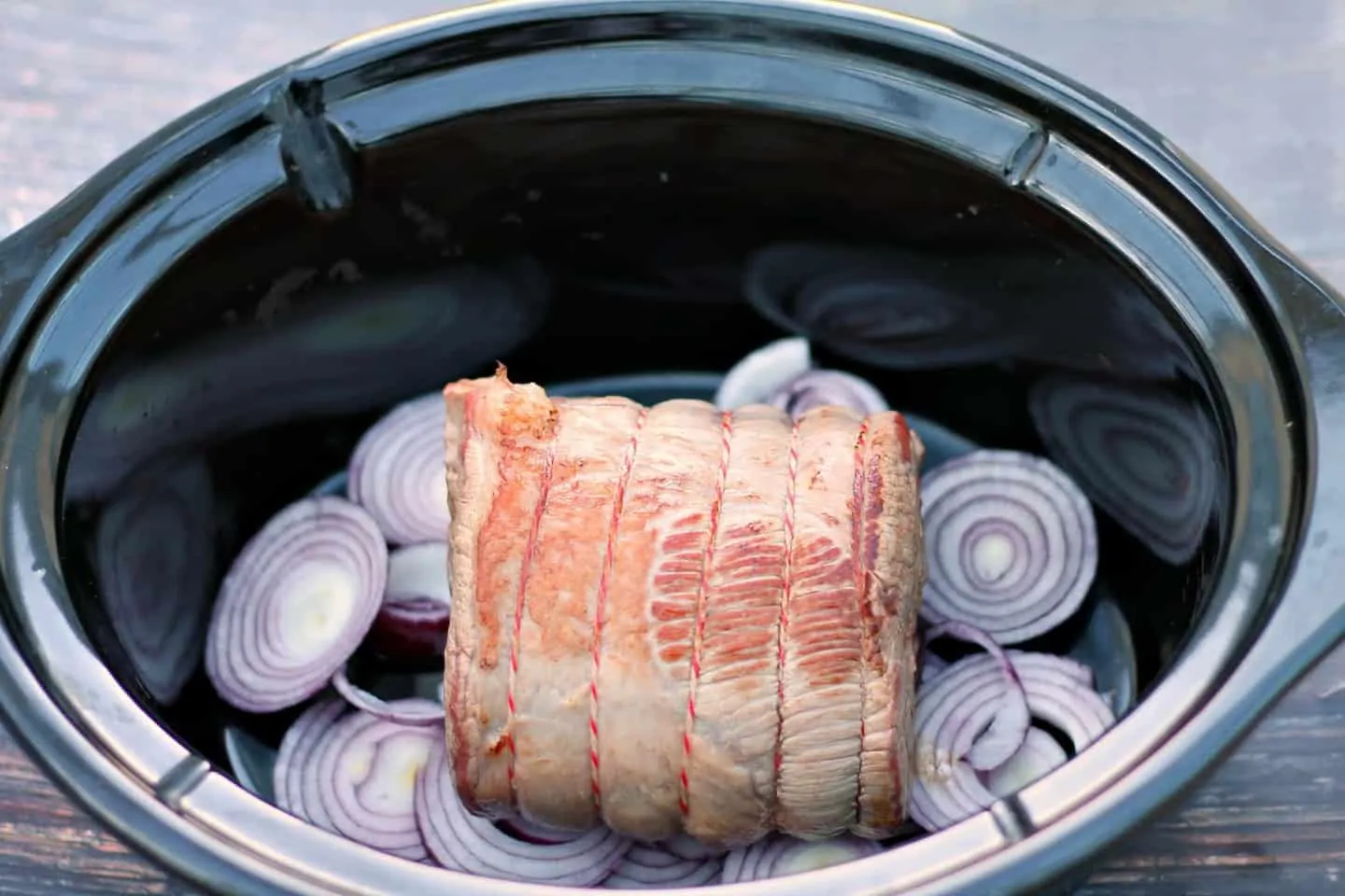 Beef brisket in slow cooker on bed of onions.