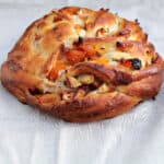 Couronne (crown) bread filled with apricots and dried fruit, on a grey fabric background.