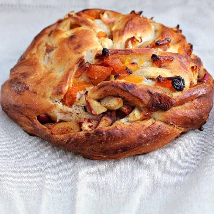Couronne (crown) bread filled with apricots and dried fruit, on a grey fabric background.