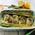Chicken breast with herbs and asparagus in a serving dish.