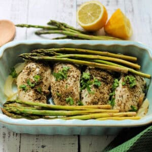 Chicken breast with herbs and asparagus in a serving dish.