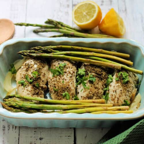 Chicken breast with herbs and asparagus in a serving dish.