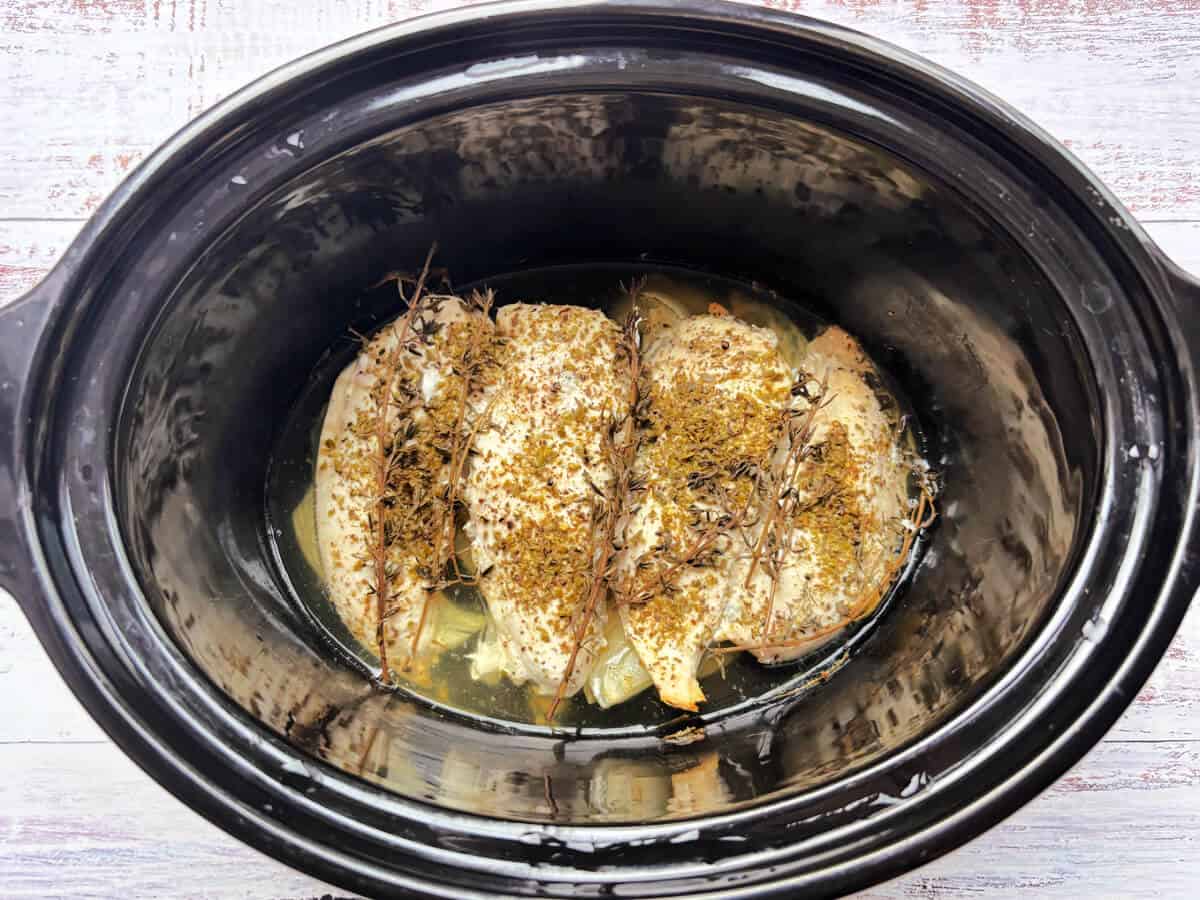 Cooked chicken breasts in slow cooker pot.