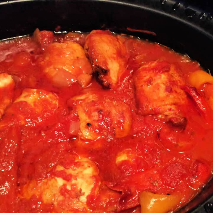 Chicken thighs in a tomato sauce in a slow cooker.