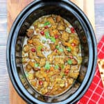Lamb stew with vibrant coriander and pomegranate garnish, in black dish.