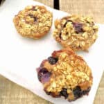Baked oat cups with blueberries, on baking parchment.